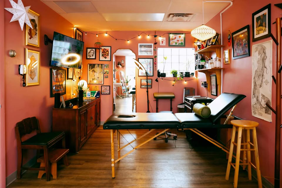 Tattoo room with black bench, ring lights, and framed flash on the walls